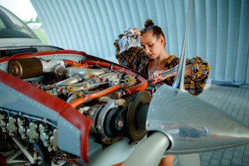 A girl repairs an airplane engine