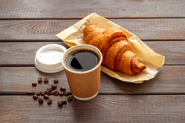 One paper cup of coffee with croissant. Takeaway coffee with snack