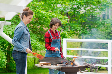 Family barbecue mom and daughter grilling with in a country house outdoors