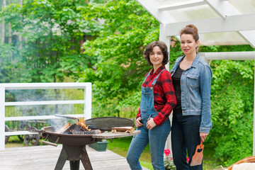 Family barbecue mom and daughter grilling with in a country house outdoors