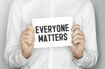 Man holding a paper card with text Everyone matters
