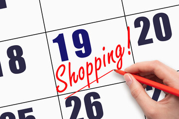 19th day of the month. Hand writing text SHOPPING and drawing a line on calendar date.