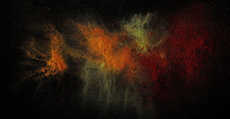 Various spice explosion, turmeric, ground lemongrass, cayenne pepper isolated on black background and texture