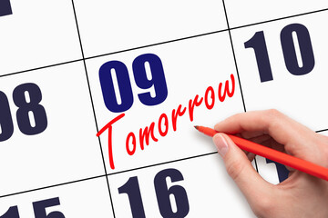 9th day of the month. Hand writing text TOMORROW on calendar date.