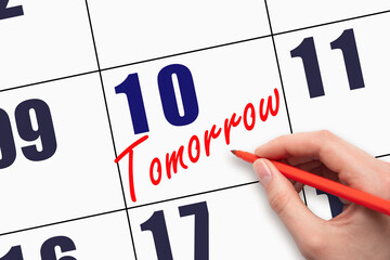 10th day of the month. Hand writing text TOMORROW on calendar date.