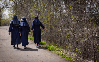Trois religieuses robe bleues qui marchent dans un sentier.