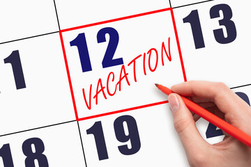 12th day of the month. Hand writing text VACATION on calendar date.