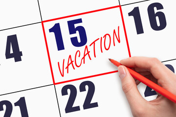 15th day of the month. Hand writing text VACATION on calendar date.