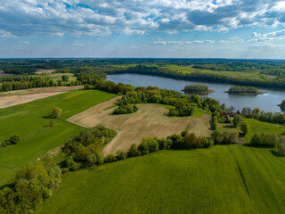 Beautiful drone nature landscape of fields, meadows, forest and lake - sunny day in Poland, Mazury aerial view