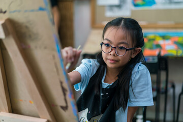 Young girl asian sitting and painting watercolour artwork to develop abilities and improve mental health at home .Female artist drawing with inspiration.