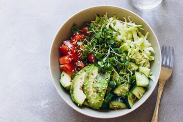 Summer green healthy salad with avocado, arugula microgreens, cucumber, cabbage and tomatoes