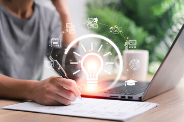 Education learning online or developing idea at home concept, Women use laptop online learning and take the example test on document at home and light bulb Education icon on a virtual screen