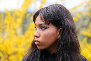 Fototapeta premium Close-up portrait of an African woman in profile against a yellow background of plants.
