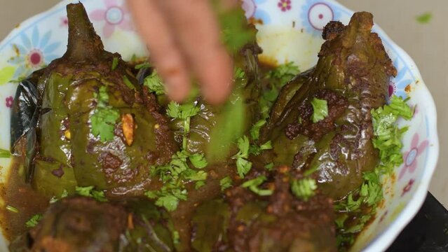 Egg plant or brinjal curry in a white bowl garnishing with coriender leaves. .