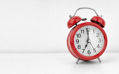 Red alarm clock on white wall background