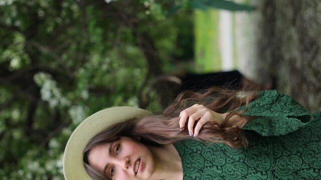 Woman with natural makeup, floral cosmetics for skin of the face, girl posing in flower branches of blooming apple tree in spring. Vertical Video