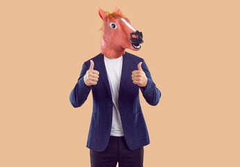 Creative studio shot of man wearing business suit and funny animal masquerade horse mask with silly...