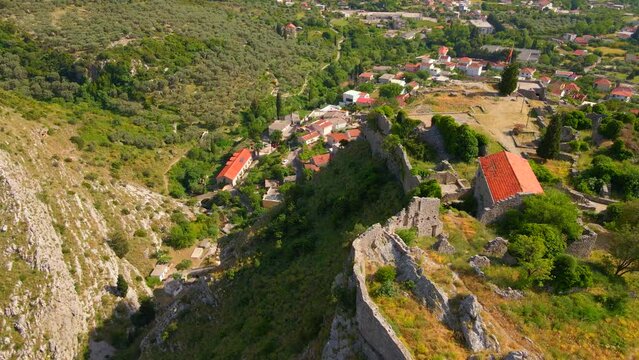 This aerial stock video captures the stunning ruins of the Old Bar or Stari Bar, a historical landmark in Montenegro. The drone footage showcases a bird's eye view of a stone fortress and an aqueduct