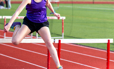 Obraz premium One girl hurdling running over a hurdle during a race