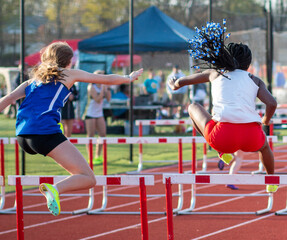 Obraz premium Two girls racing in the hurdles during a track meet