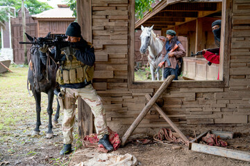 Group of men with soldier and arab clothes stand with holding gun and point to enemy also stay in...