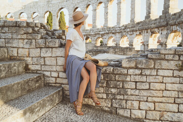 Beautiful tourist woman visiting the sights in Pula, Croatia. Vacation in Europe at summertime.