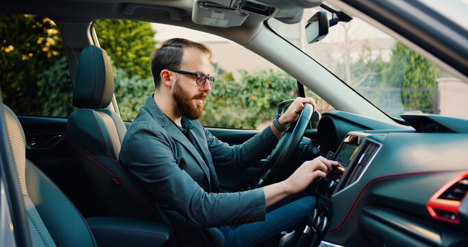 Side view of caucasian businessman making scrolling and typing text on touch screen monitor on car.