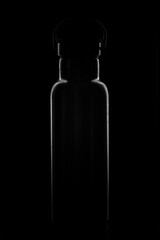Abstraktes, dunkles Low-Key Foto einer Edelstahl Trinkflasche, hochkant