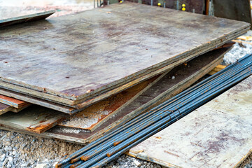 Rebar and construction materials stacked haphazardly on a wet construction site.