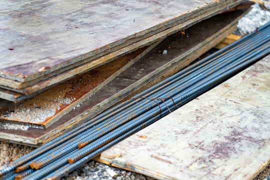 Rebar and construction materials stacked haphazardly on a wet construction site.