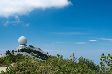 The top of the Mont Ventoux in Vaucluse,  with the Radôme, a civil aviation radar. Pines tree in the foreground. A blue sky.