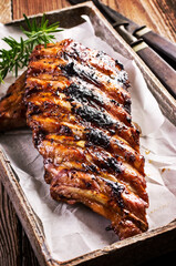 Barbecue veal spare ribs with hot honey chili marinade served as close-up on a design stone tray