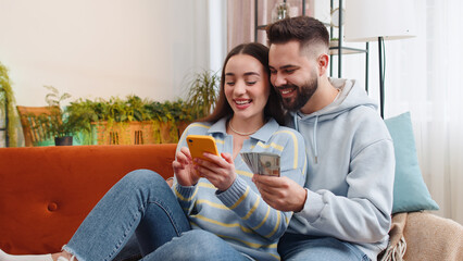 Planning family budget. Smiling family married couple man woman counting money cash, use smartphone calculate domestic bills at home. Husband wife satisfied of income for planned vacation, gifts