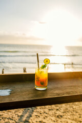 Photo of fresh orange juice on sunny day on the beach, sunset on Bali