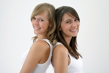 portrait of two beautiful girls, standing back to back, smiling