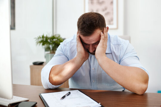 Stress, headache and business man in office with documents for burnout, mental health risk or depression. Depressed, pain and tired person or employee with fatigue, brain fog or anxiety and paperwork