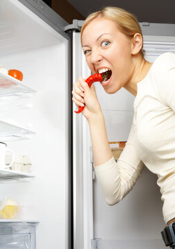 A hungry woman is peeping into an empty fridge
