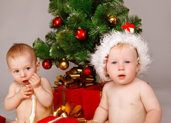 Two baby santas in front of the Xmas tree