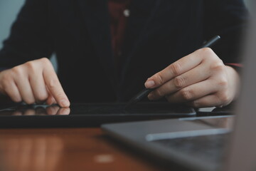 Asian Businesswoman Using laptop computer and working at office with calculator document on desk, doing planning analyzing the financial report, business plan investment, finance analysis concept.