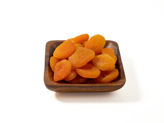 Wooden bowl of dried apricots on a white background, selective focus. Dried apricots close up.