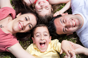 Parents and kids laying on the floor with heads together, outdoors