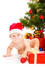 Baby in a red hat sitting under the Christmas tree