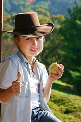 Friendly mountain boy sitting on the balcony in the afternoon eating fresh fruit and giving the thumbs up