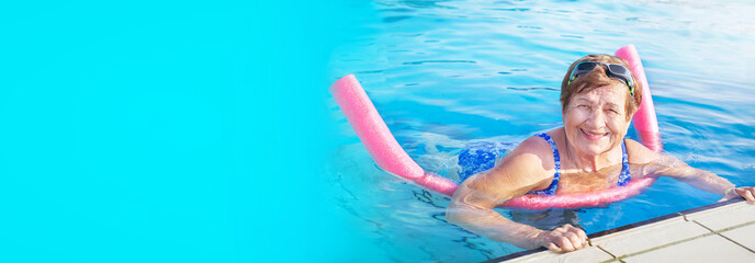 Banner of senior woman (over age of 50) doing aqua fitness with swim noodles in swimming pool....