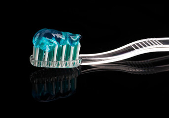 toothbrush and paste over black reflective background