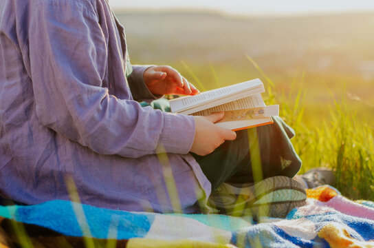 Woman reading a book on a hill at sunset