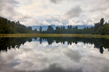 Spiegelung an einem ruhigen Waldsee bei trüben Wetter.
