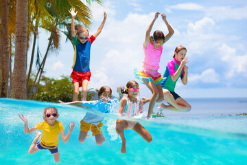 Kids jump into swimming pool. Summer water fun.