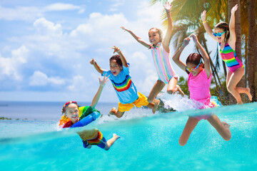 Kids jump into swimming pool. Summer water fun. - obrazy, fototapety, plakaty