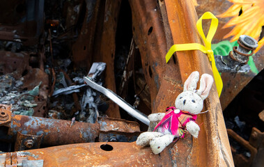 Close-up of a child's toy in ruins after a fire. A soft toy among a burned-out car. Spoiled...